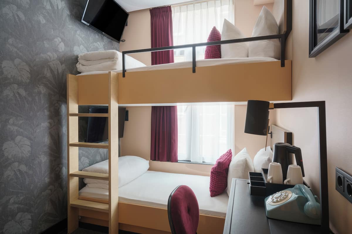 Habitación con literas, un escritorio, un teléfono y una ventana con cortinas.