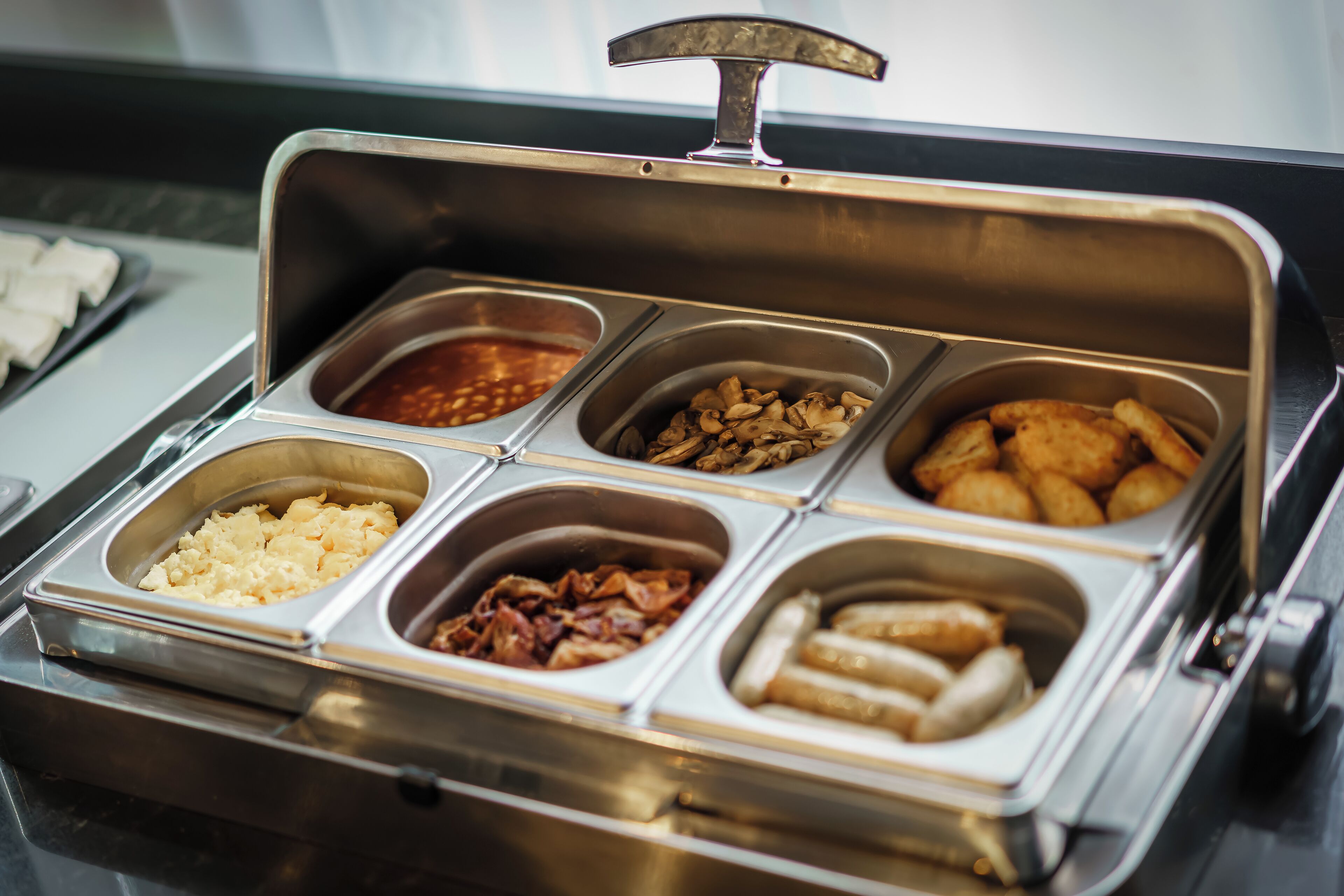 A buffet with various food items including tofu, mushrooms, and fried items.