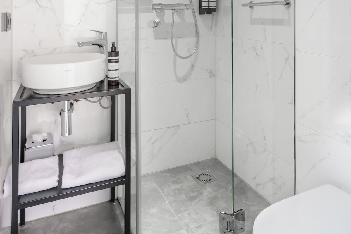 Uma casa de banho moderna com chuveiro de vidro, lavatório branco e sanita.