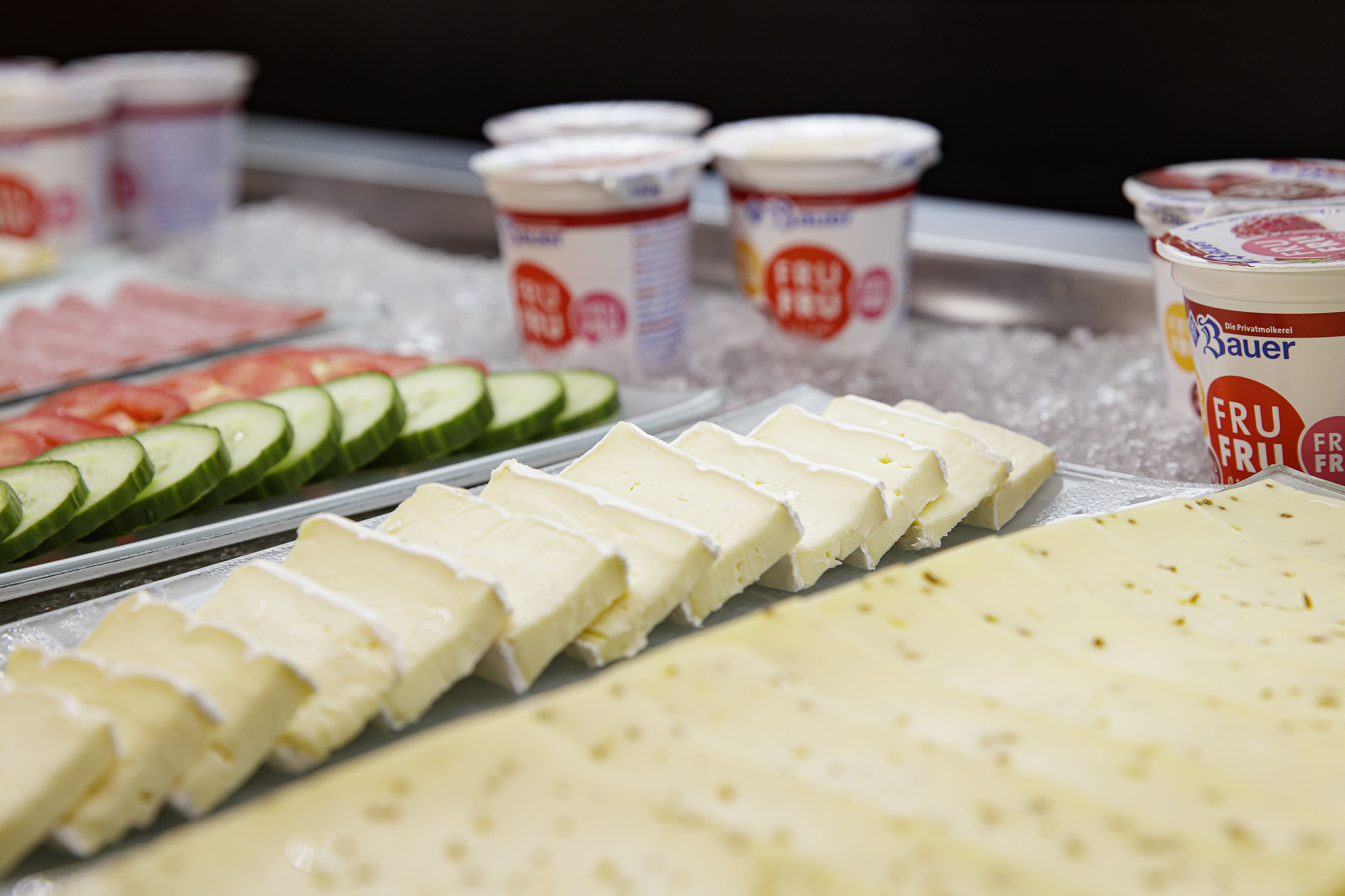 Une variété de fromages et de yaourts sont présentés sur un présentoir.