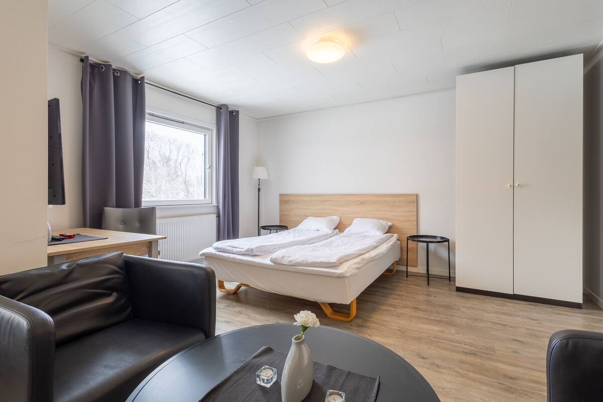 Ein modernes Hotelzimmer mit Bett, Schreibtisch, Stuhl, Sofa und Esstisch.