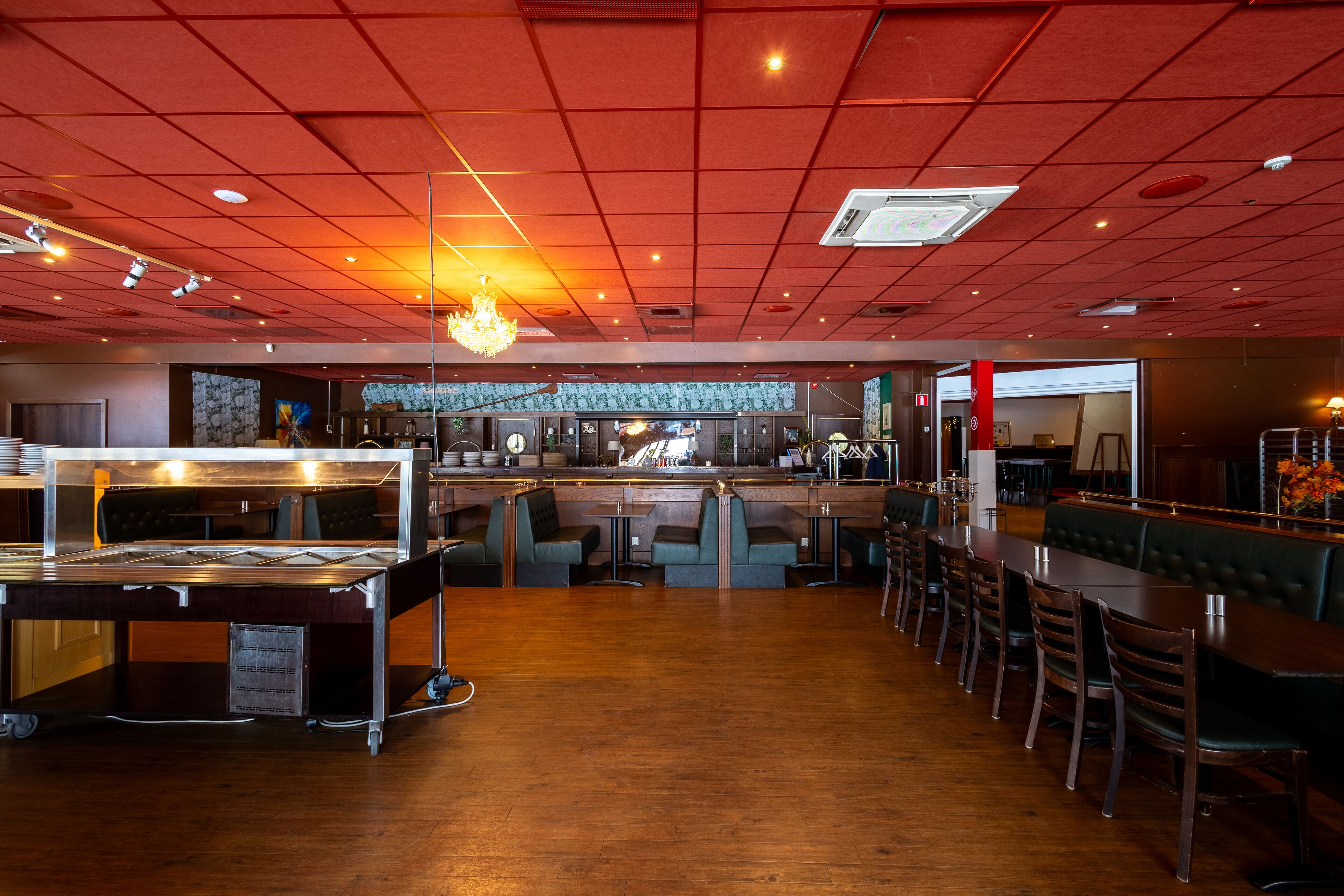 A restaurant with a long counter, booths, and a bar area.