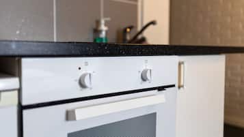A kitchen with a black countertop, white appliances, and a tiled backsplash.
