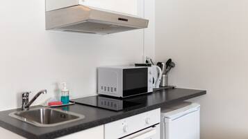A modern kitchen with a stainless steel sink, a microwave, and a compact oven.
