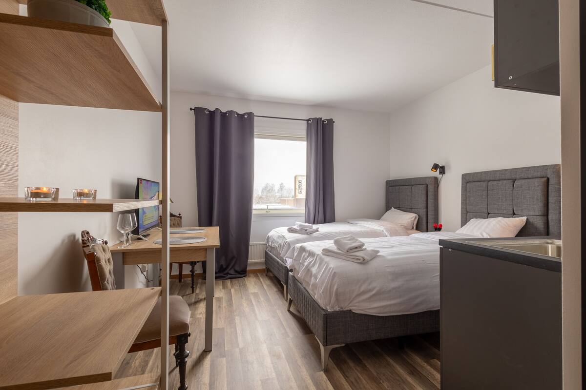 Ein modernes Hotelzimmer mit zwei Betten, einem Schreibtisch und einem Computer.