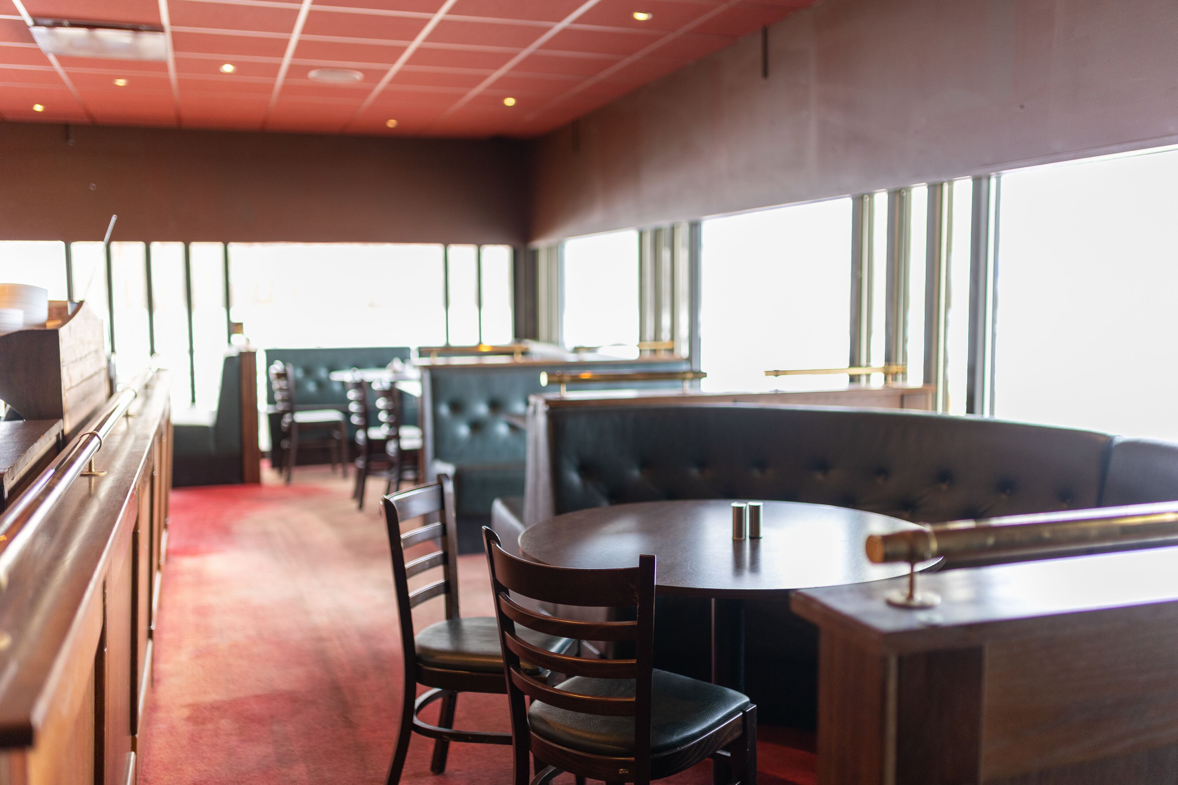 Ein Restaurant mit Bar, Sitzgelegenheiten und großen Fenstern.