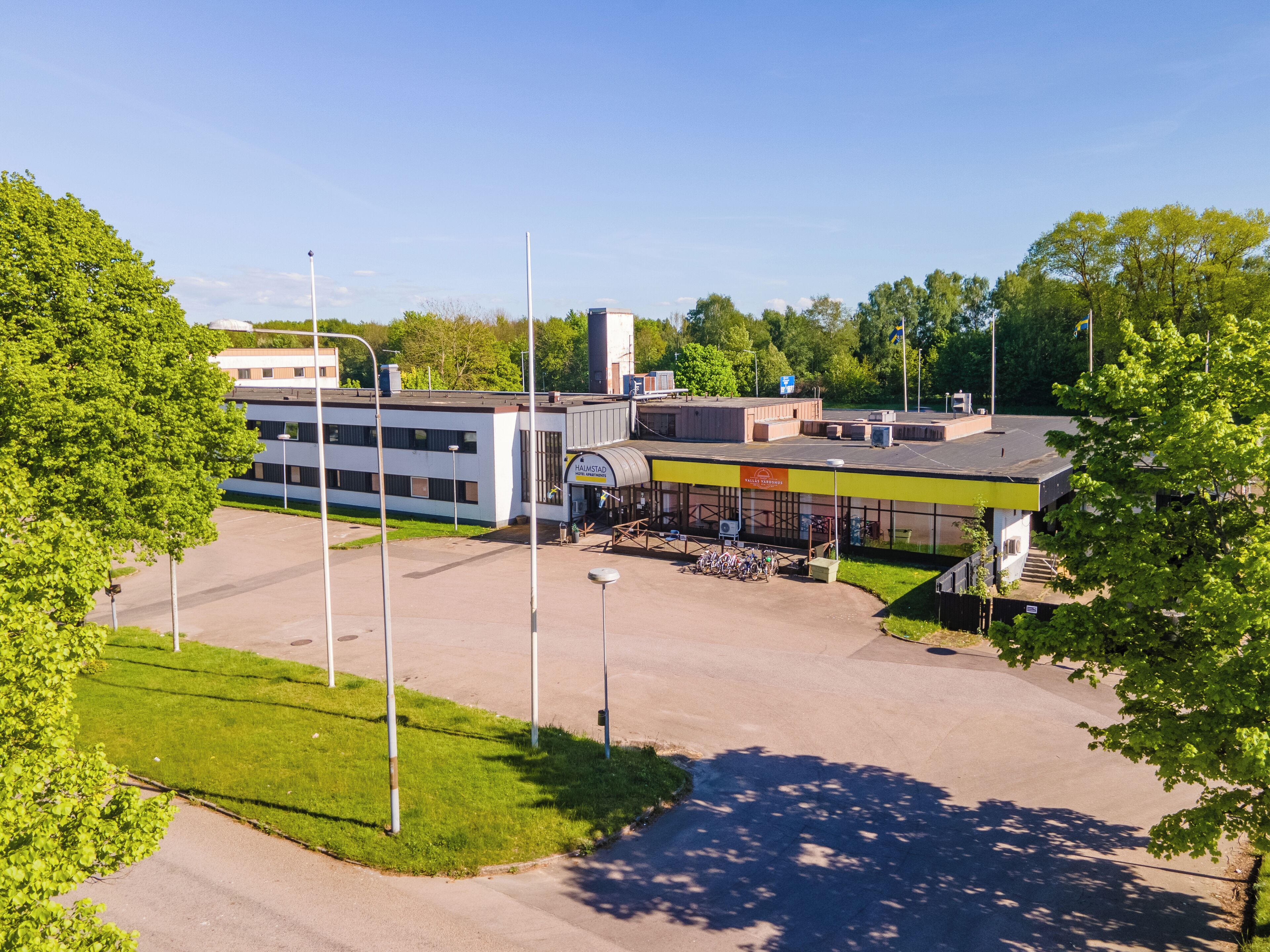 A parking lot with a building that has a sign reading "HALMSTAD".