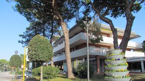Un edificio a più piani con balconi, un lampione e una fila di fioriere.
