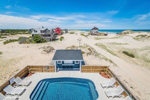 A beachfront property with a swimming pool, lounge chairs, and a view of the ocean. - The Salty Sand Dollar - 4X4 Carova Beach, Ocean View, Pool, Hot Tub, Pool Table, Arcade Game (4x4 - Carova Beach)