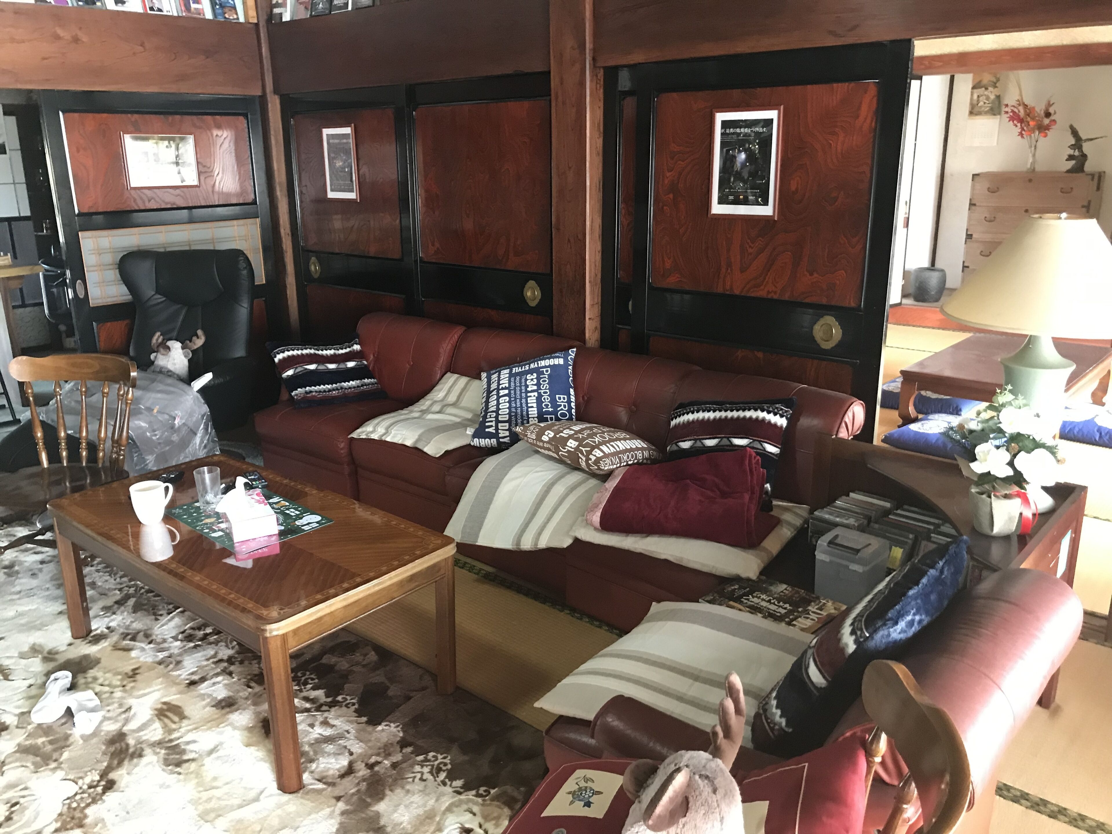 A cozy living room with a brown leather sofa, a wooden coffee table, and a patterned rug.