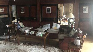 A traditional Japanese-style room with tatami flooring, a low wooden table, a sofa, and a chair. - A house with a rural garden (魚津市)