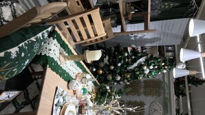 A dining area with a Christmas tree, wooden chairs, a table with a green tablecloth, and a clock on the wall. - A house with a rural garden (魚津市)