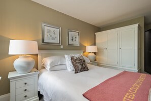 A neatly arranged bedroom with a bed, two bedside tables with lamps, a wardrobe, and framed artwork on the wall. - No5 Highpoint luxury townhouse ,2 en-suite bedrooms onsite indoor swimming pool (Saundersfoot)