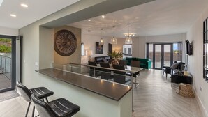 Eine moderne Küche mit Kochinsel, einer Sitzecke mit Sofas und einer großen Wanduhr.