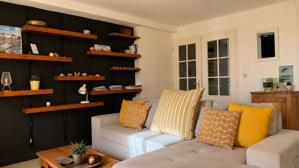 A living room with a sofa, coffee table, and wooden shelves against a wall. - Le Central (Wimereux)