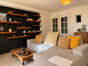 A living room with a sofa, coffee table, and wooden shelves against a wall. - Le Central (Wimereux)