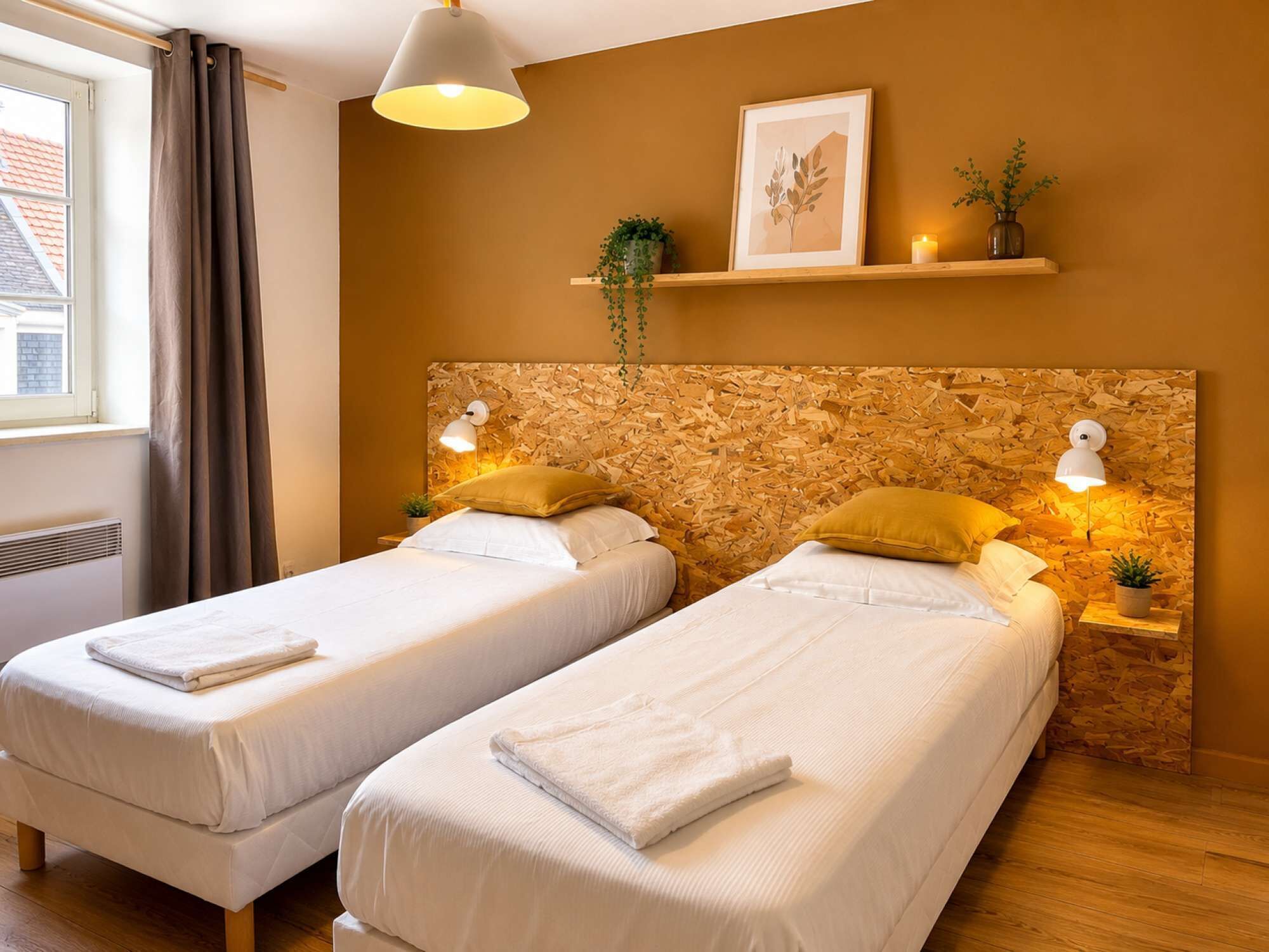 Une chambre avec deux lits, une fenêtre avec des rideaux, une étagère fixée au mur avec des plantes et une tête de lit à l’aspect bois.