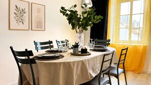 A dining table set for four with chairs, a vase with green plants, and framed artwork on the wall. - Le Central (Wimereux)