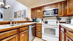 Fully equipped kitchen with sink, dishwasher, stove, and microwave.