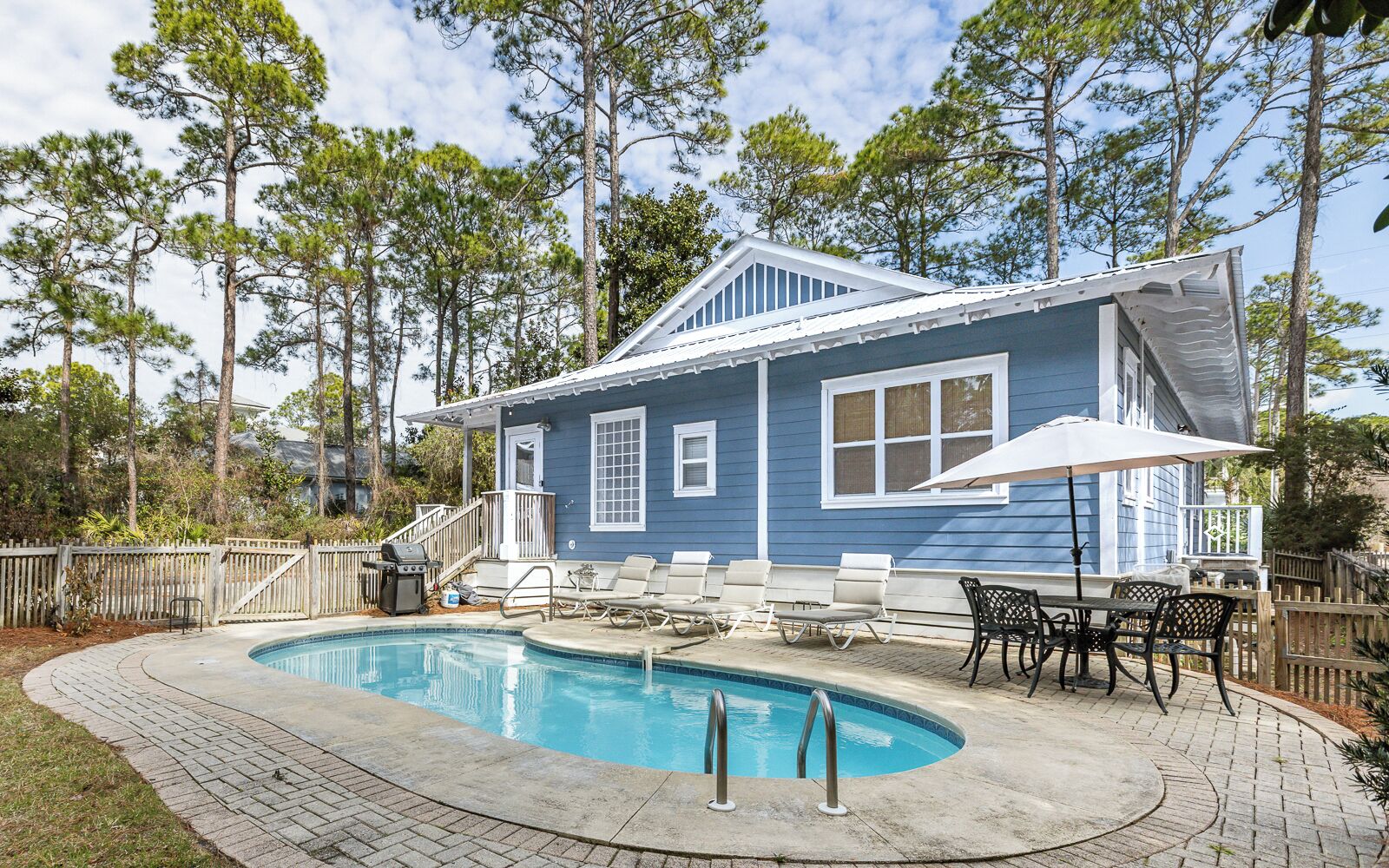 Une maison avec une piscine, du mobilier d’extérieur et une terrasse en bois.