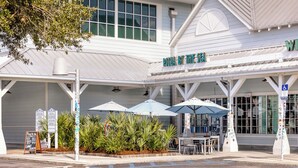 Ein Restaurant namens „Pizza by the Sea“ mit Außenbereich und Sonnenschirmen.