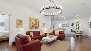 Ein geräumiges Wohnzimmer mit einer roten Ledersitzgruppe, einem weißen Couchtisch und einer modernen Chandelier.