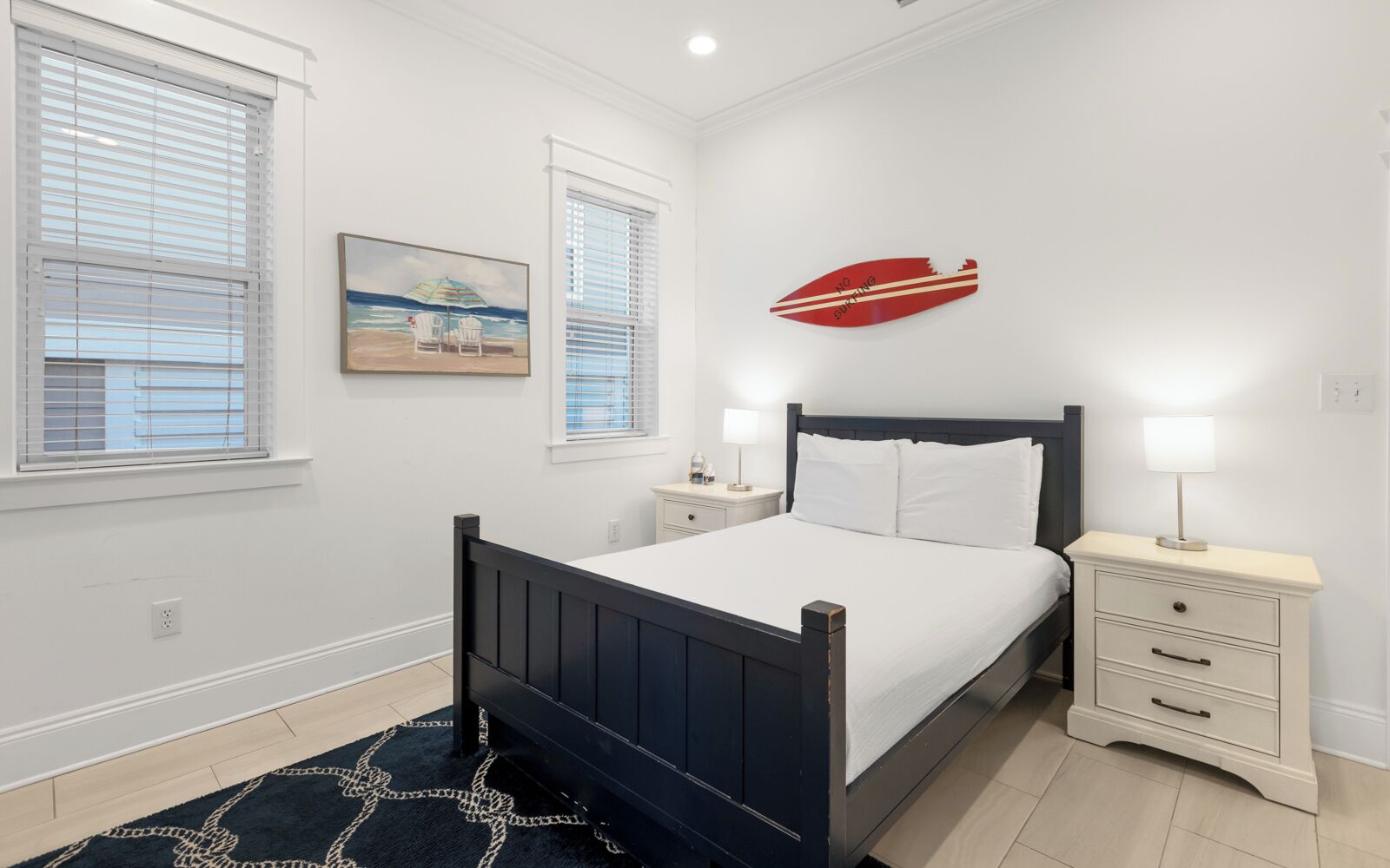 A bedroom with a bed, bedside tables, a nightstand, a painting, and a decorative wall piece.
