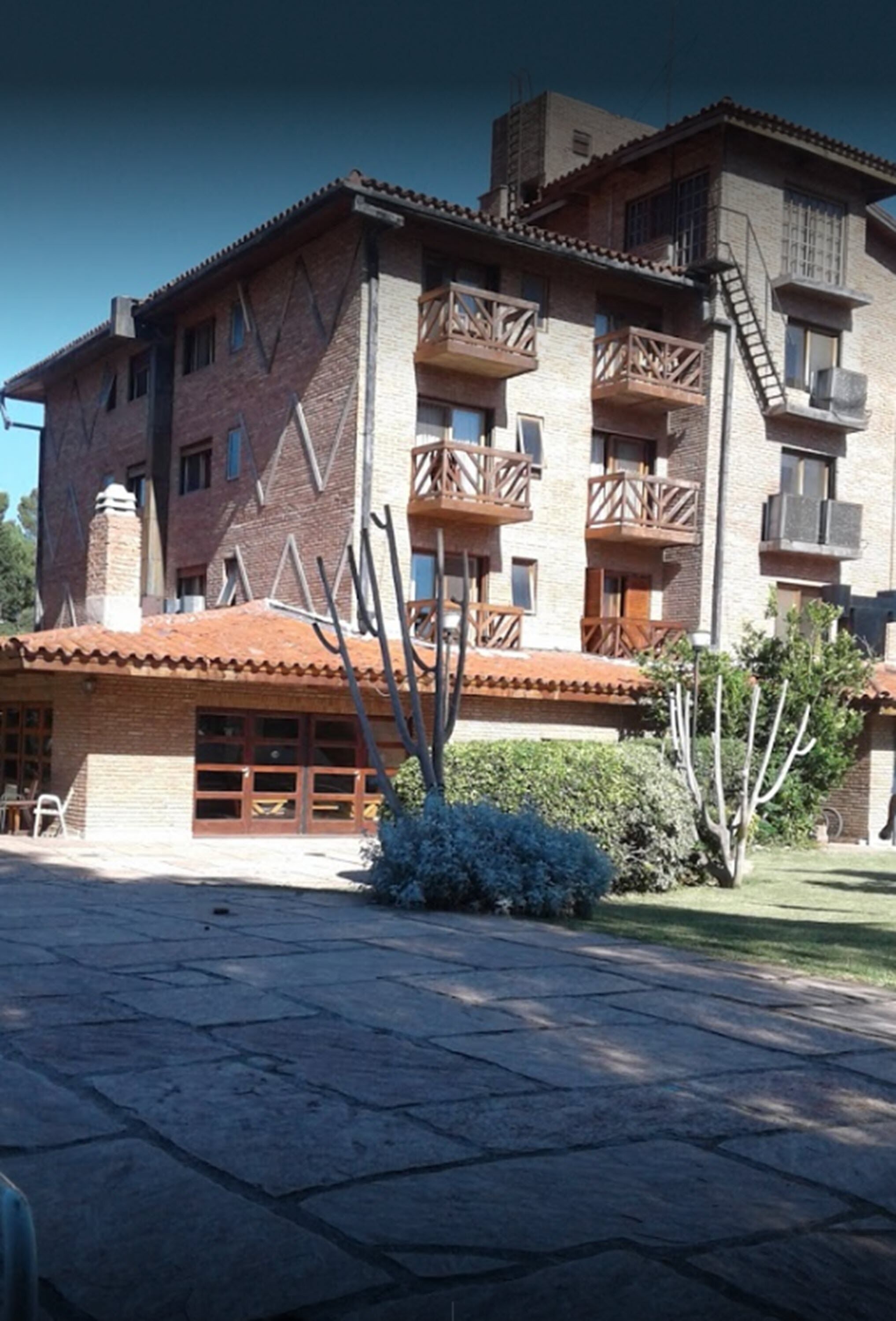 A multi-story building with a brick facade, wooden balconies, and a garage entrance.