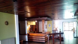 A spacious room with wooden flooring, a central wooden staircase, and a reception desk. - Kuntur Posada (Capilla del Monte)