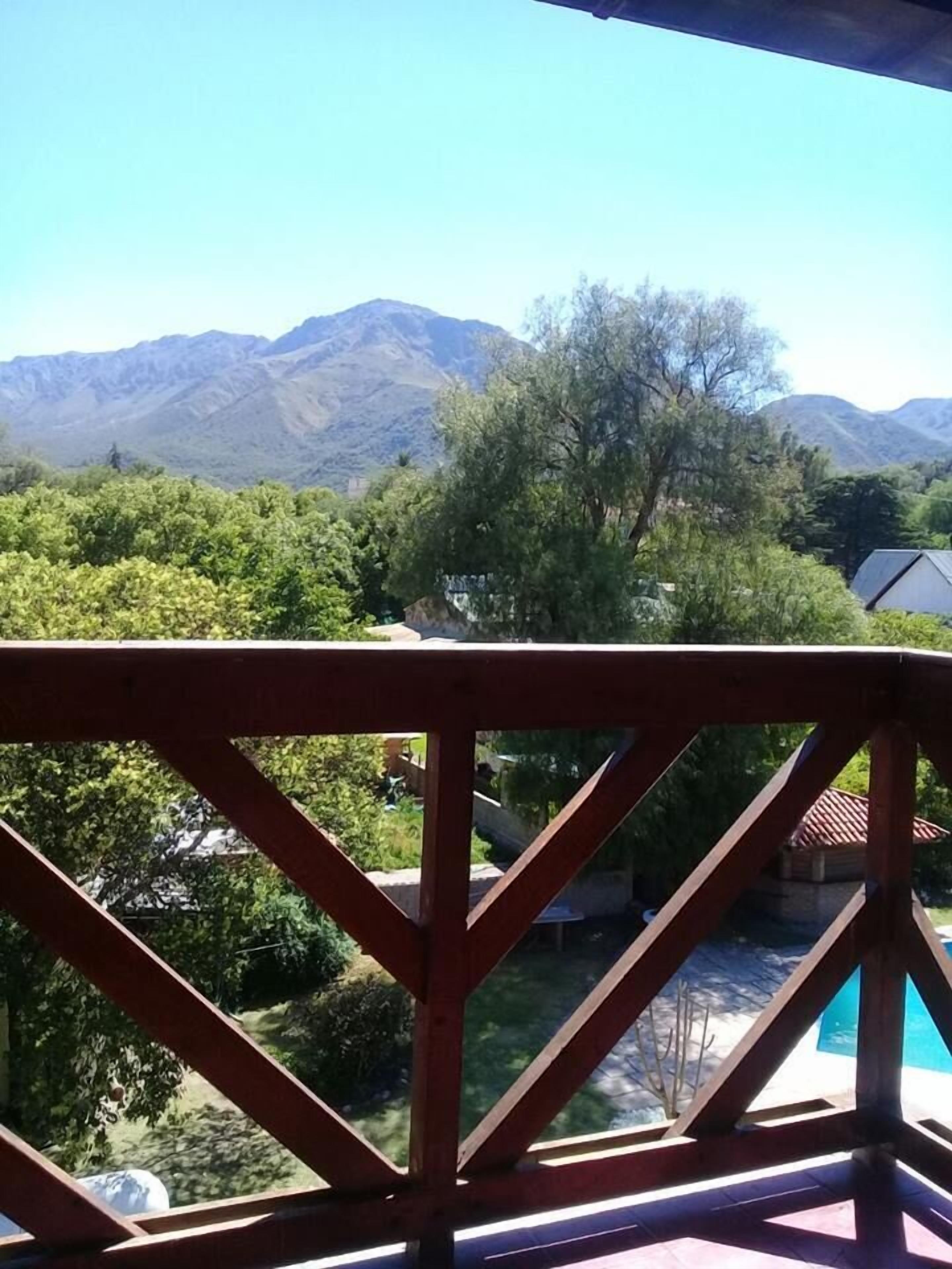Un balcón con vistas a montañas y follaje.