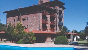 A multi-story building with a swimming pool in front. - Kuntur Posada (Capilla del Monte)