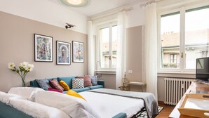 A bedroom with two beds, a sofa, a TV, and artwork on the wall. - 2 Bedrooms Apartment in the City Center (Milan)