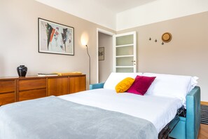 A bedroom with a bed, a dresser, a wall-mounted lamp, and a door. - 2 Bedrooms Apartment in the City Center (Milan)
