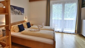 Una cama doble con estructura de madera, dos almohadas y una escultura de toalla.