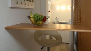 Una cocina con un bol de fruta sobre una encimera de madera, una estufa y una repisa con plantas en la pared.