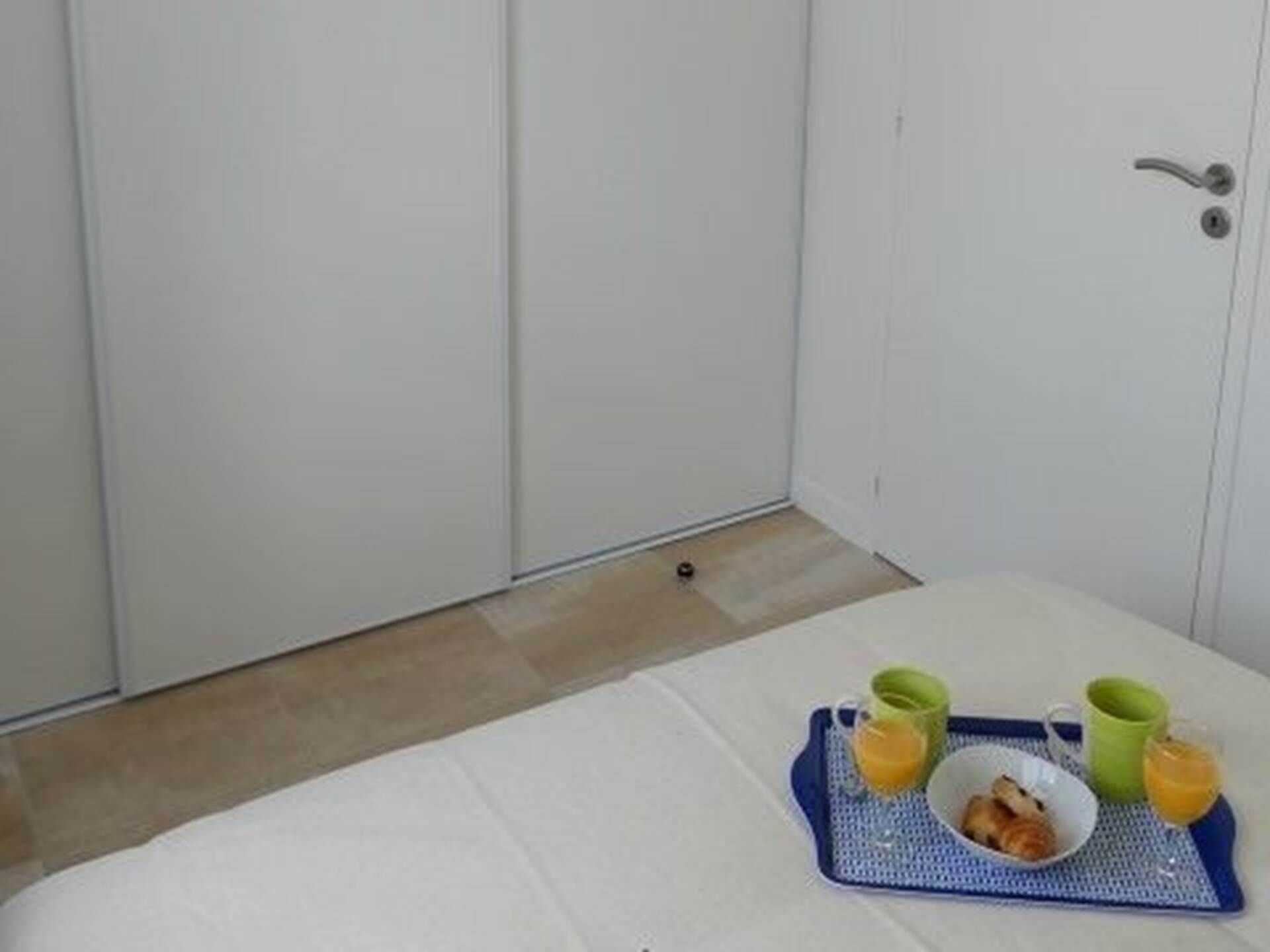 A small room with a bed, a tray with breakfast items, and a door.