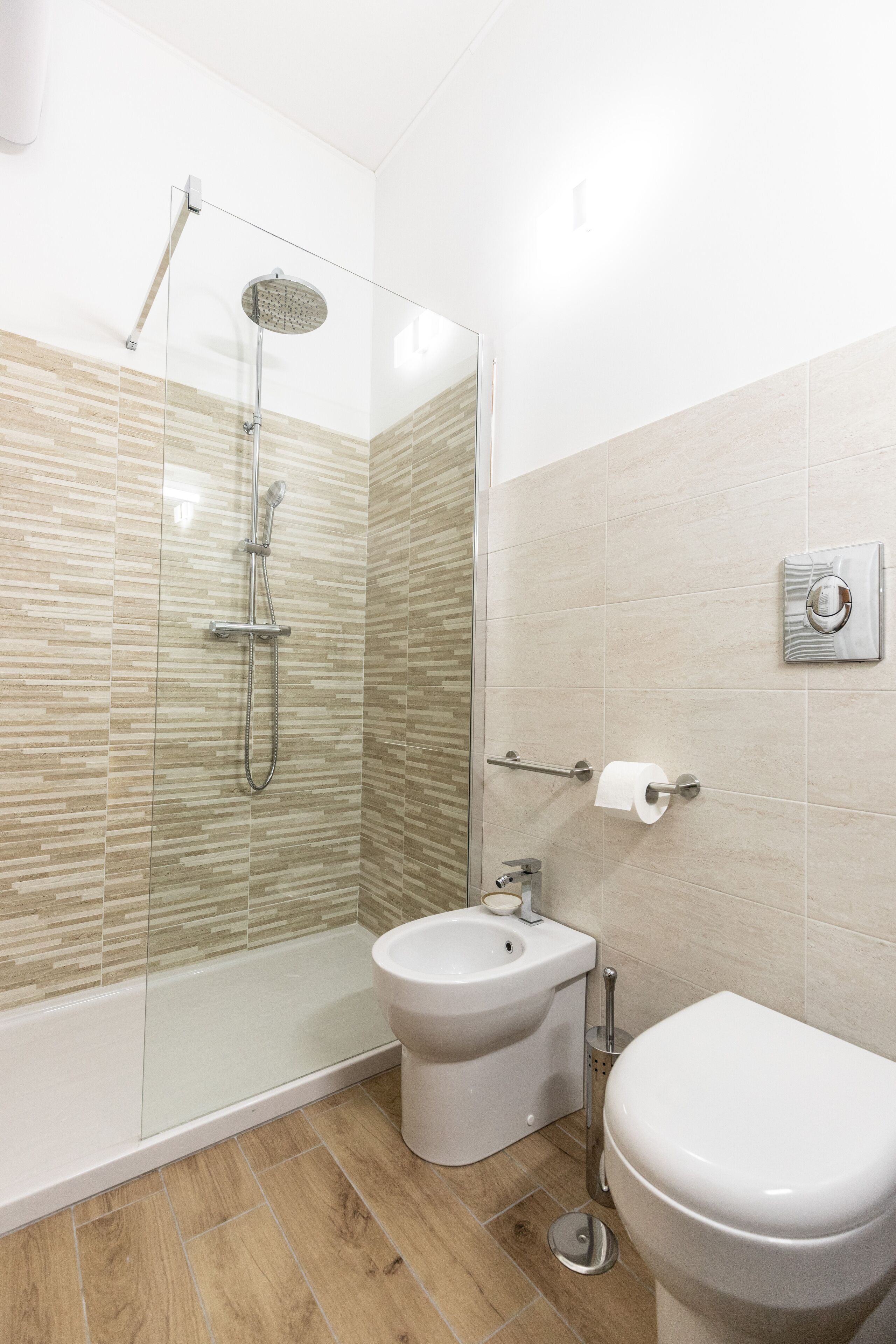 Un baño moderno con ducha de vidrio, un bidé y un inodoro.