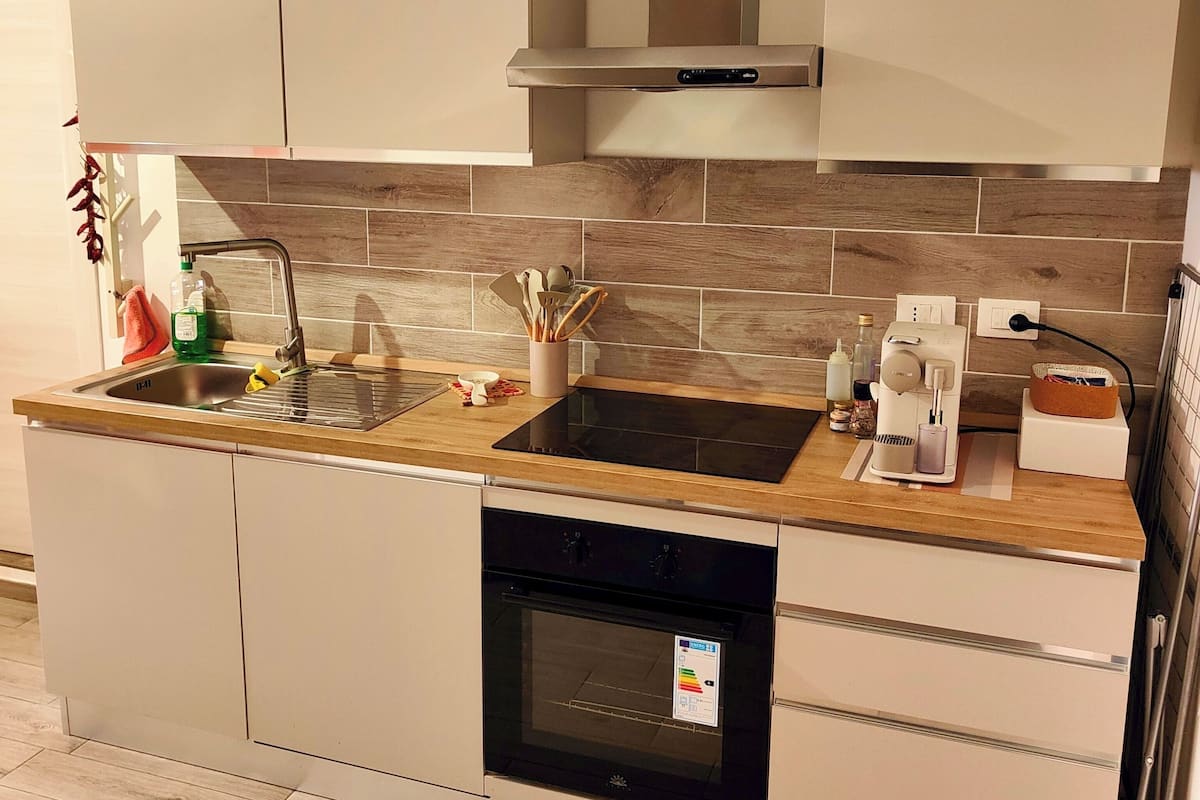 A modern kitchen with two sinks, a built-in oven, and a stainless steel range hood.