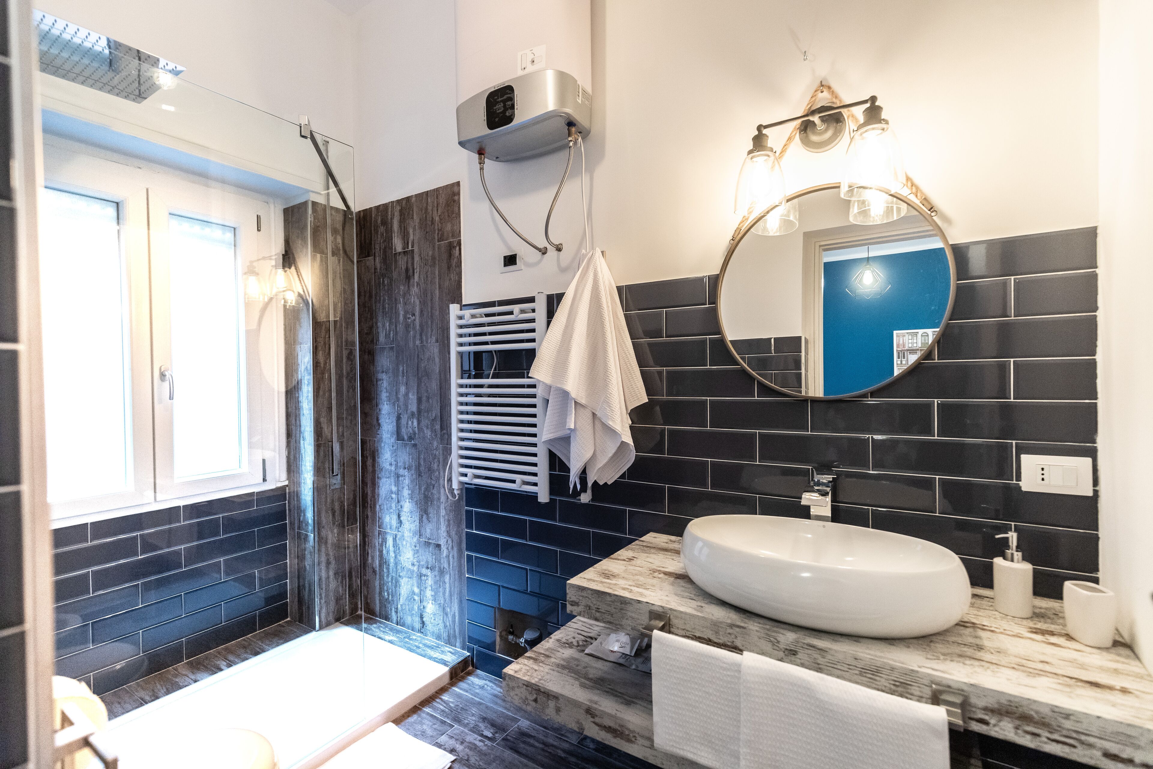 A modern bathroom with a large mirror, a white sink, and a towel rack.