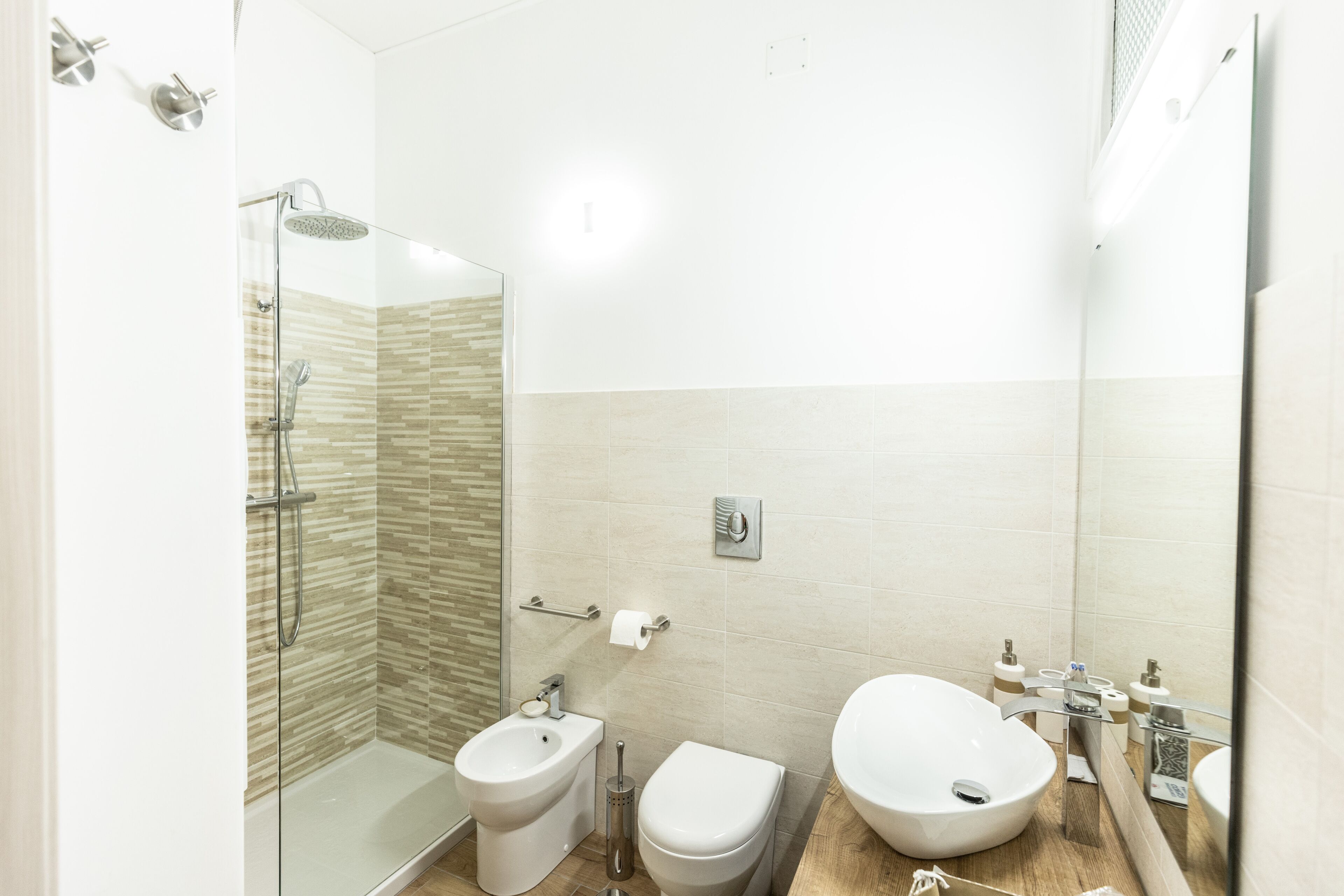 Et moderne badeværelse med bruseniche, bidét, toilet og stor vask.