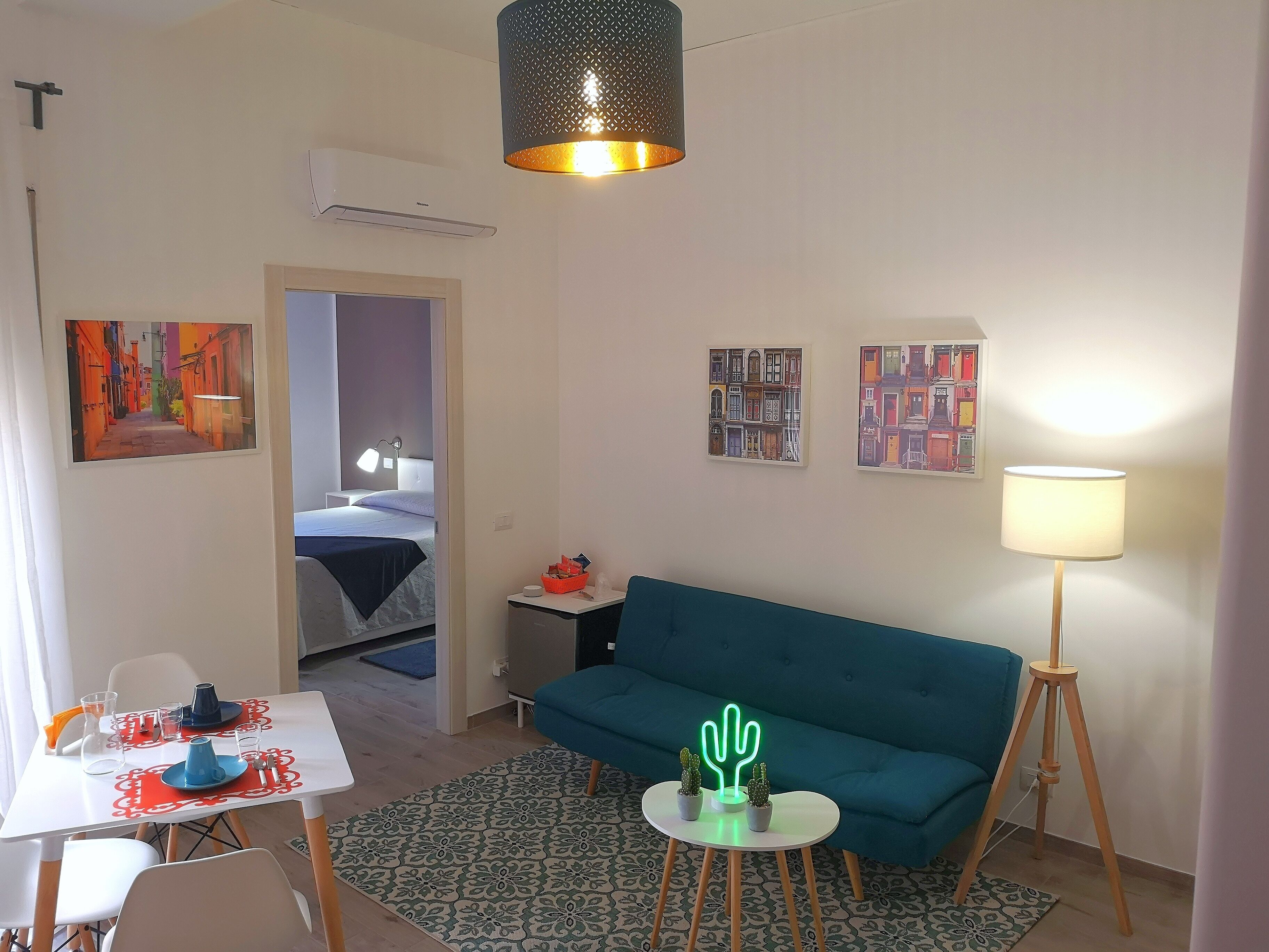 Un soggiorno moderno con un divano, un tavolo da pranzo e un piccolo tavolino con una lampada.
