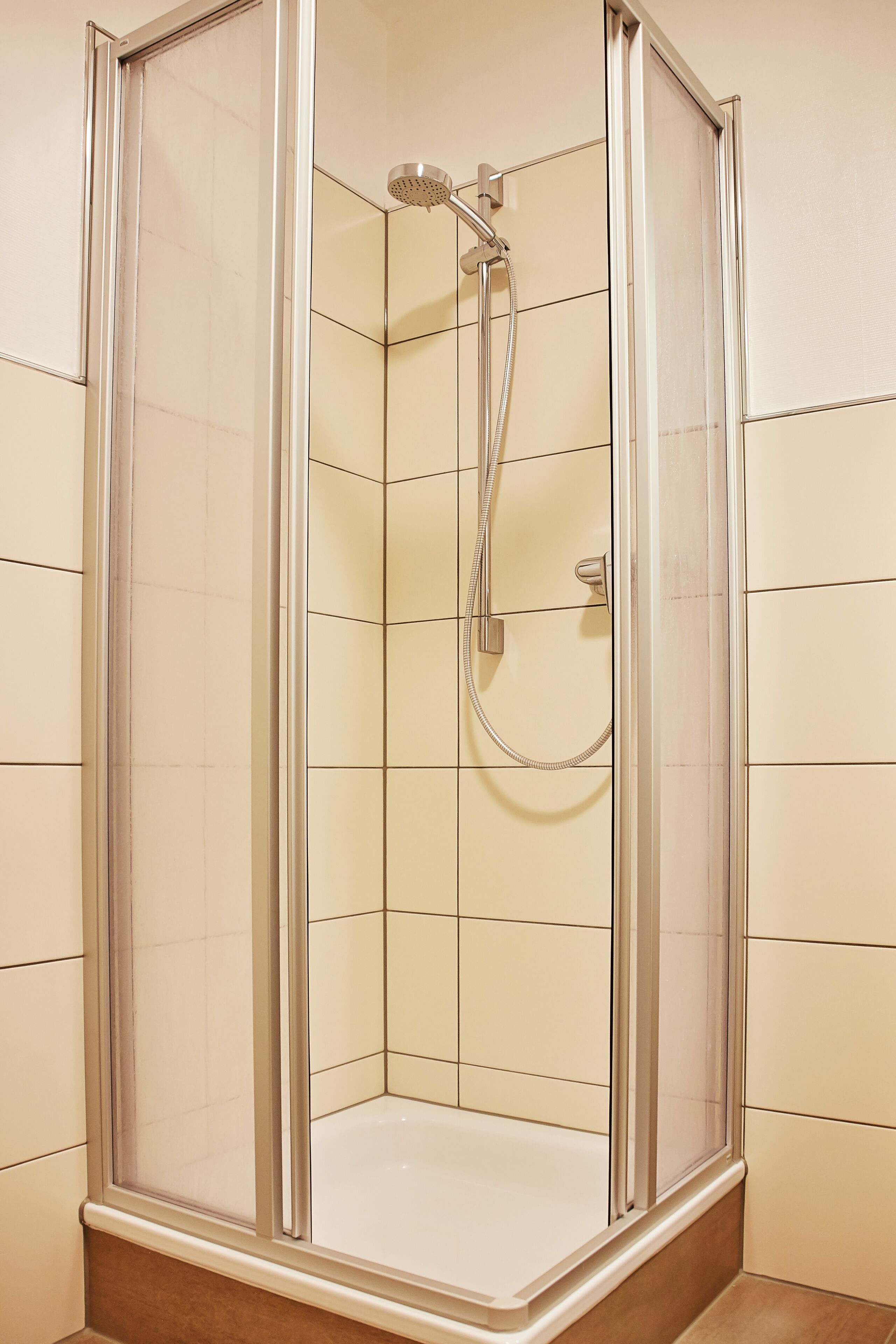 A walk-in shower with a glass door, tiled walls, and a showerhead.