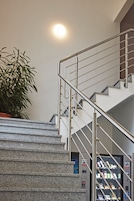 Una escalera con barandas de metal, una planta en maceta y máquinas expendedoras.