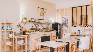 Cocina compacta con muebles de madera, un refrigerador y una zona de comedor con sillas.
