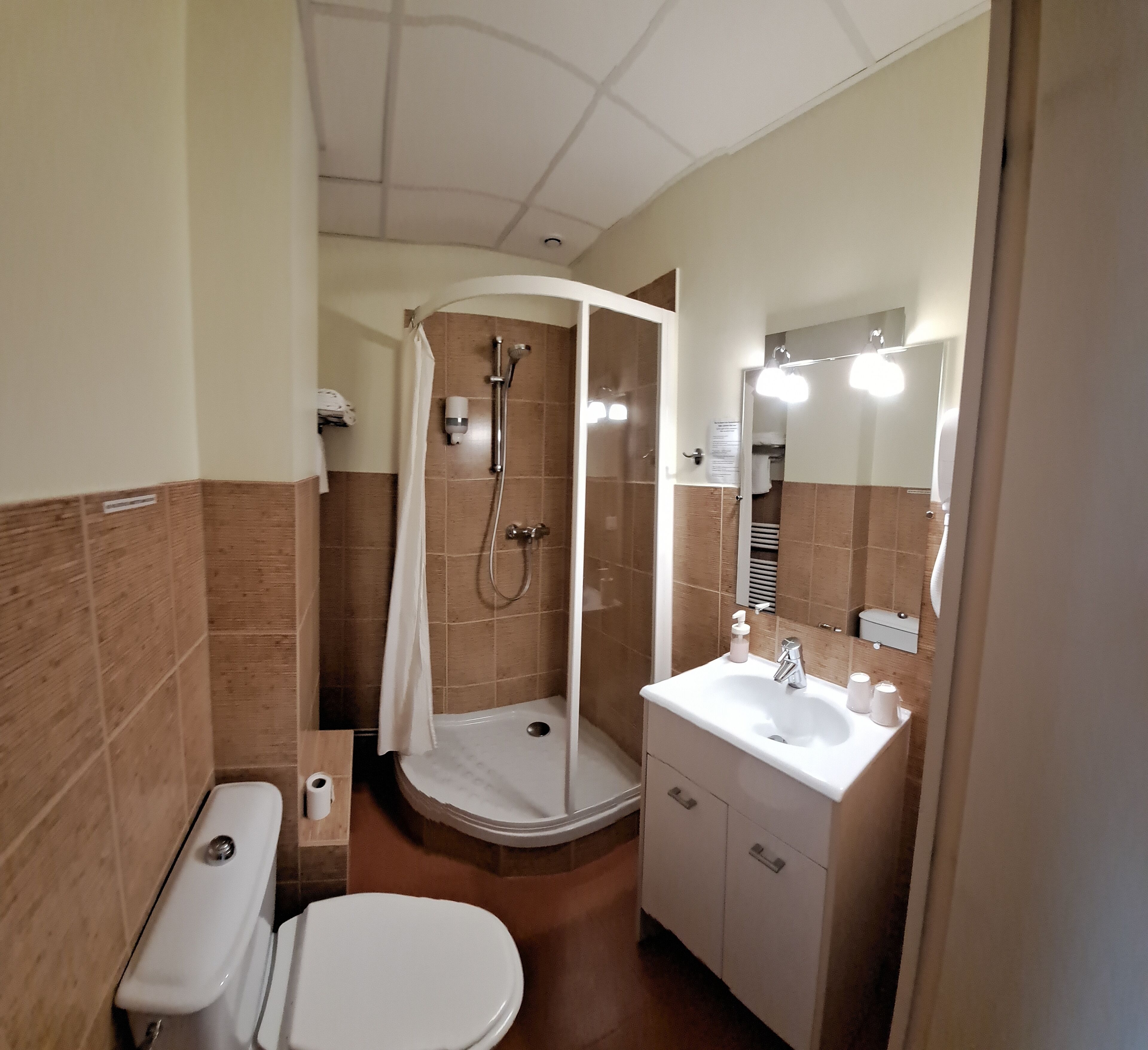 A bathroom with a shower, toilet, sink, and mirror.