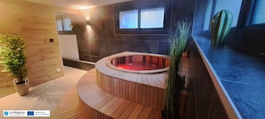 Un área de spa moderna con un banco de madera, una bañera de hidromasaje y una planta en maceta.