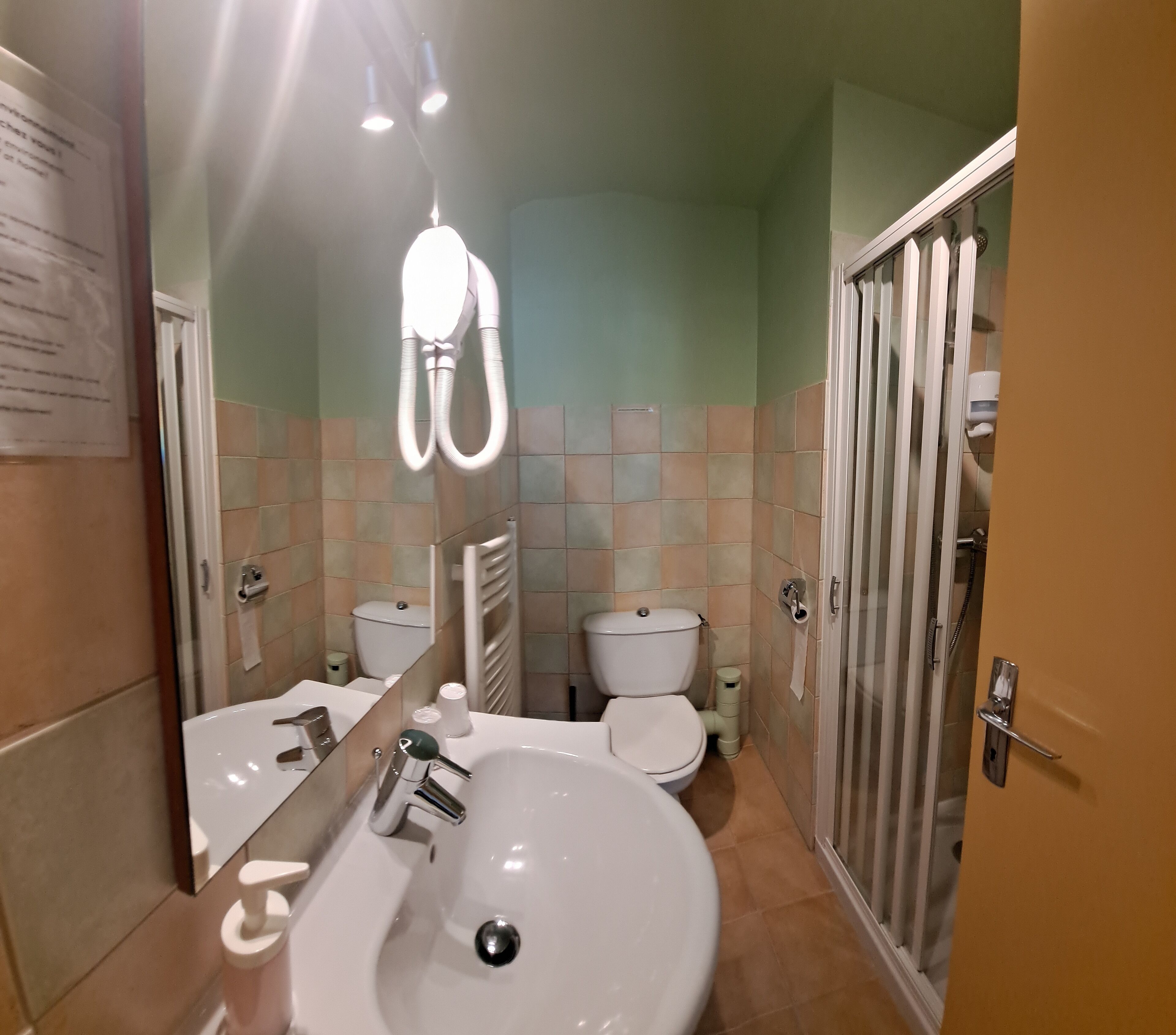 A bathroom with a sink, mirror, two toilets, and a shower area.