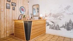 Un mostrador de recepción con detalles de madera, cuadros en la pared y un gran mural de un paisaje montañoso.