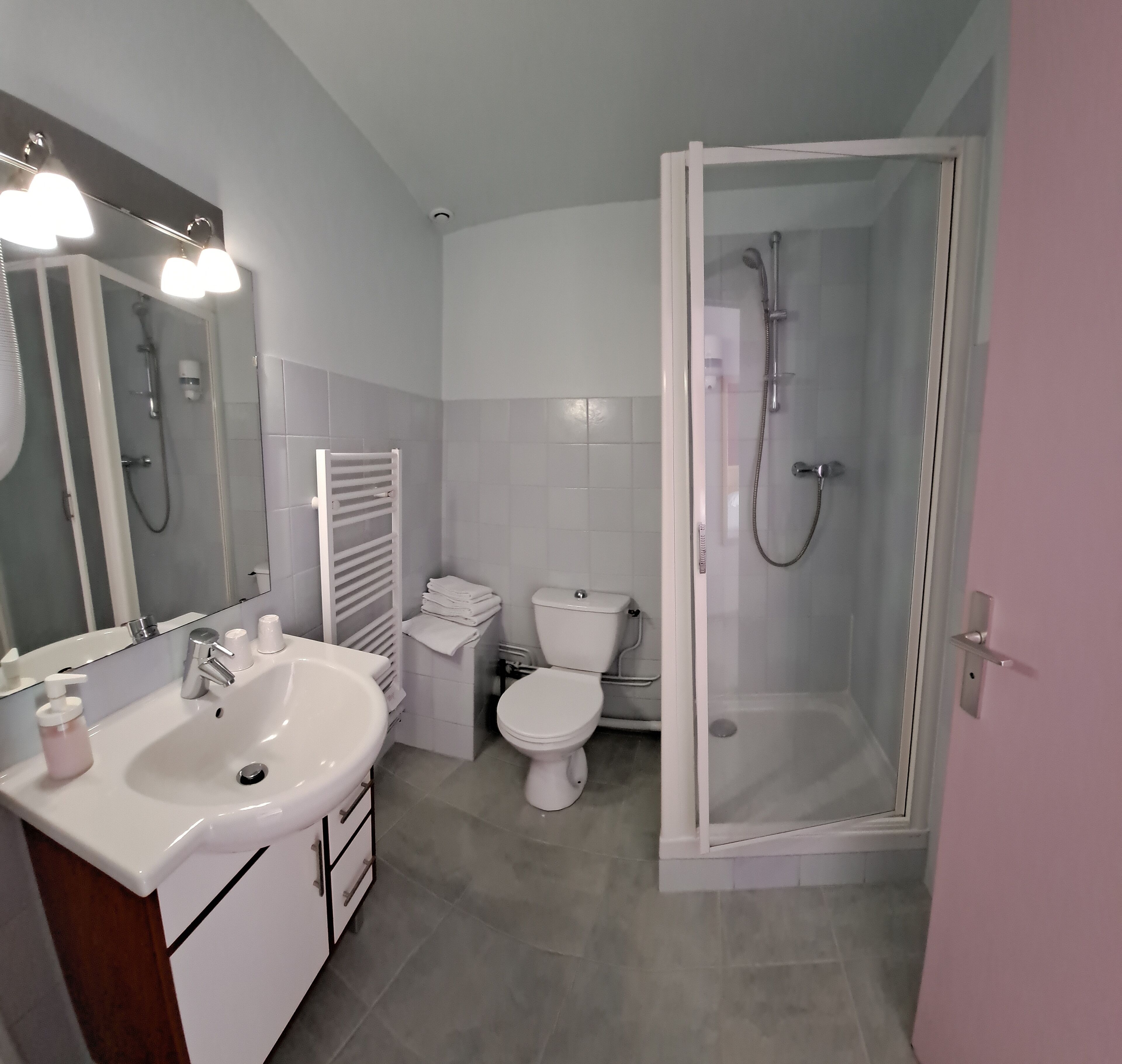 Une salle de bain moderne avec un lavabo blanc, un miroir, des toilettes et une douche.
