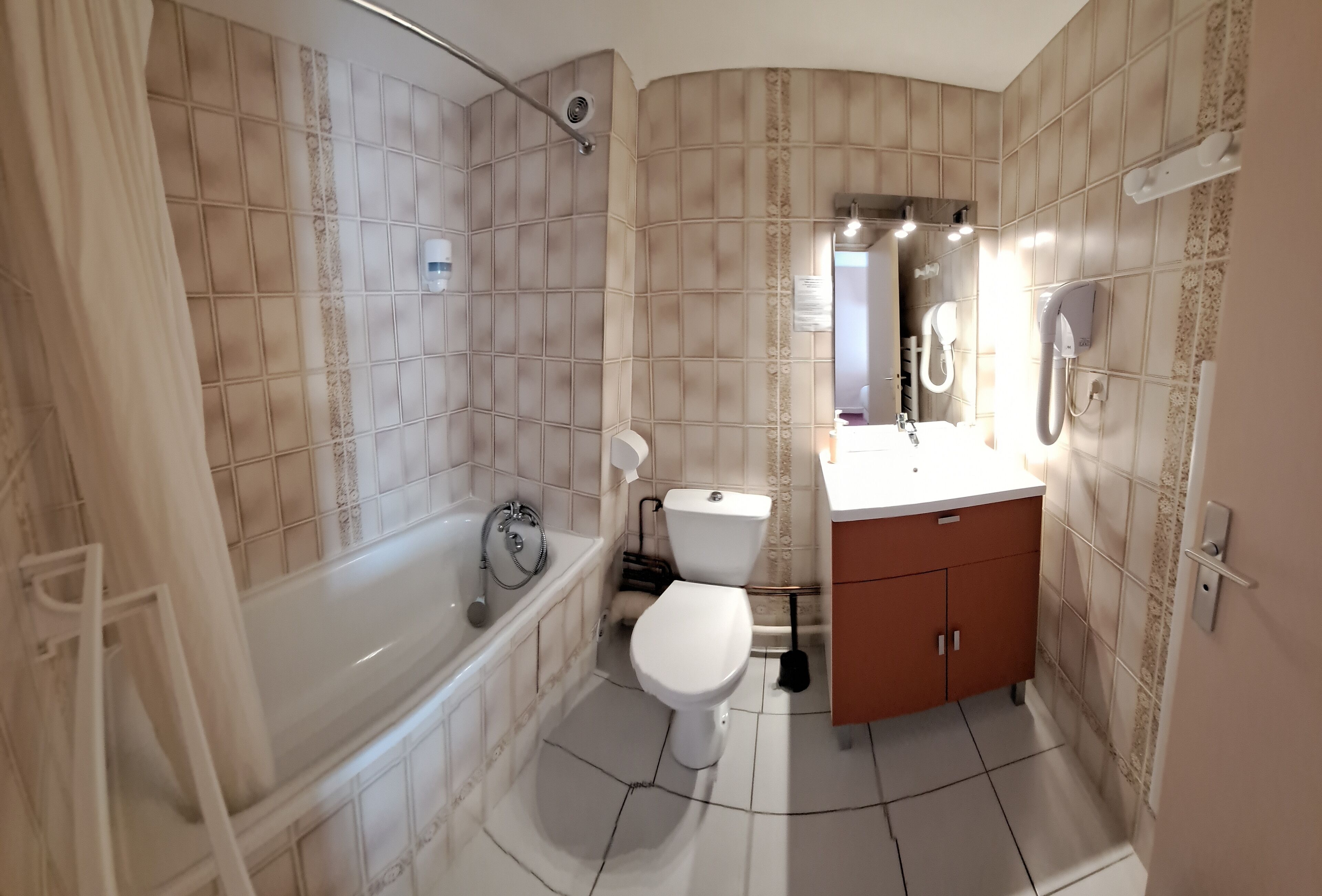 Un baño con bañera, inodoro y tocador con espejo.